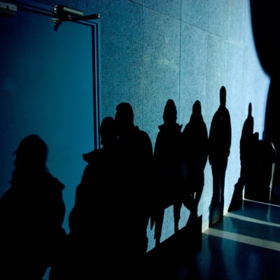 Skuggor av personer syns på en vägg i mörkret.