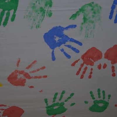 Fingermålad teckning med handavtryck i blått, grönt, gult och rött.
