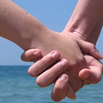 Två människor håller varandra i handen.