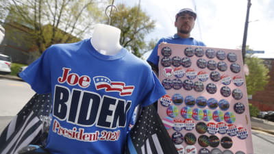 En man står och säljer blåa skjortor med texten "Joe Biden president 2020".