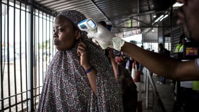 Granskning av en kvinnas kroppstemperatur på en granskningsplats i Kongo i juli 2019.