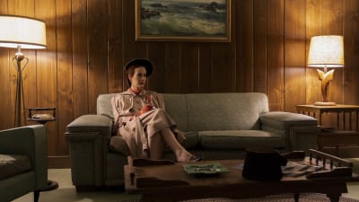 På bilden syns skådespelaren Sarah Paulson i rollen som Mildred Ratched. Hon är iklädd 1950-tals kläder och sitter på en soffa ensam i ett rum.
