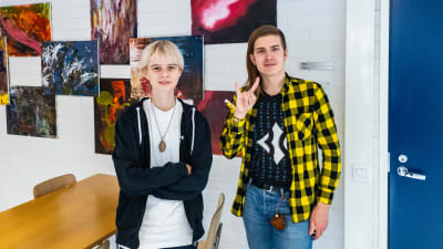 Två ungdomar tittar mot kameran, den ena visar "rockhornen" med handen