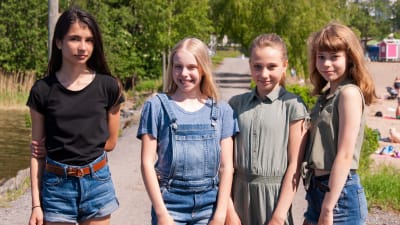 Fyra flickor står på led på en grusväg.
