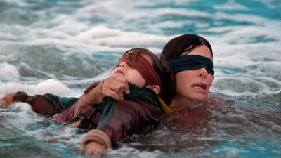 En bild från filmen Bird Box – två personer i vattnet med ögonbindlar.