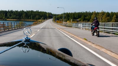 Vy inifrån en Mercedes som blir omkörd av en moped.