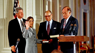 Ruth Bader Ginsburg svärs in i USA:s högsta domstol den 10 augusti 1993. Hon har sin hand på bibeln som hennes man Martin håller i och håller upp andra handen i luften. Bredvid henne står president Bill Clinton. På andra sidan domaren William Rehnquist.