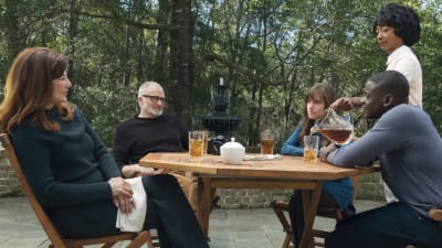 Chris (Daniel Kaluuya) sitter tillsammans med Rose (Allison Williams) och hennes familj vid ett altanbord och dricker ice tea.