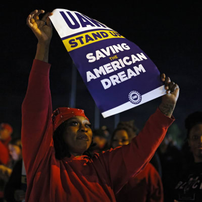 En kvinna håller uåå ett plakat där det står "räddar den amerikanska drömmen".