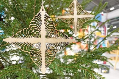 En Tomasstjärna, ett modernt fanerkors som liknar det gamla Tomaskorset med många krusiduller, hänger i en grön julgran.