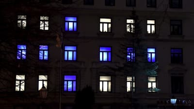 Ett höghus i Helsingfors firar självständighetsdagen med belysning i vitt och blått.