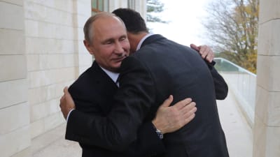 Vladimir Putin omfamnar Bashar al-Assad.