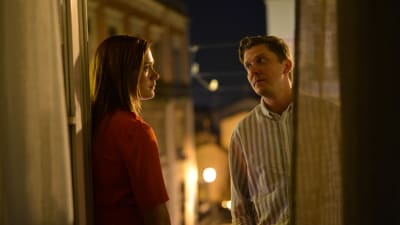 Ett äkta par spelat av Krista Kosonen och Eero Ritala samtalar i mörkret på en hotellbalkong.