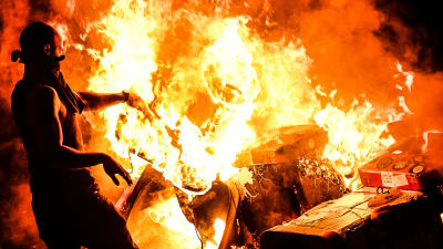 En demonstrant kastar ett föremål in i en eld. Demonstranter i Hamburg protesterar mot G20-mötet.