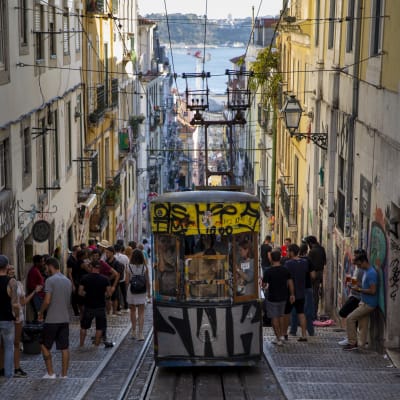 En spårvagn åker upp för en brant backe i Lissabons historiska centrum. 