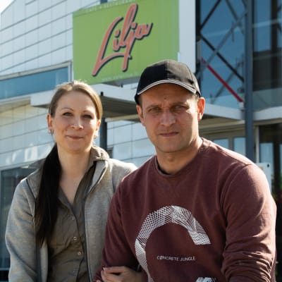 Jenny och Petri sitter utanför servicestationen och tittar in i kameran. 