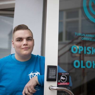 Turun ammattikorkeakoulun opiskelijakunnan hallituksen puheenjohtaja Matias Sillanmäki nojaa TUOn toimiston oveen.