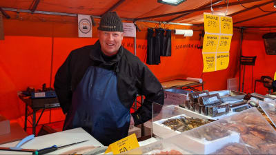 Fiskhandlare Tuomas Kajasola står bakom disken på sitt försäljningsstånd på Salutorget.