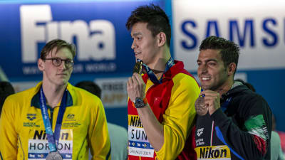 Sun Yang och Gabriele Detti poserar med sina medaljer, medan Mack Horton stirrar på Yang.
