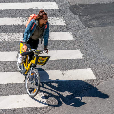 Nainen ajaa kaupunkipolkupyörällä.