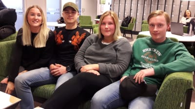 Fyra 18-åringar i soffan i skolans aula, glada, ser in i kameran.