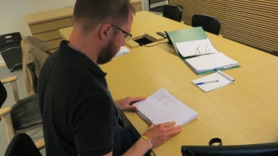Redaktör Linus Lång går igenom utskrifter av riksdagens besökarlistor.