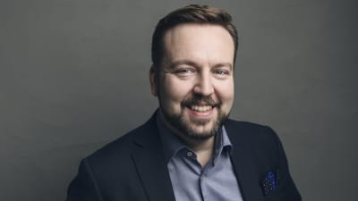 En leende man i kostym.