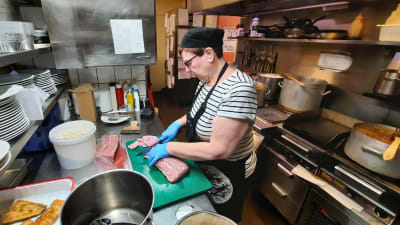 Monica Hänninen skär upp griskött på restaurang Hanna-Maria i Borgå.
