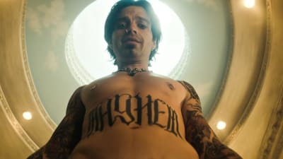 Tommy (Sebastian Stan) katsoo alasti alas kohti kameraa. Hänen vatsassaan on suurikokoinen tatuointi, jossa lukee "Mayhem".