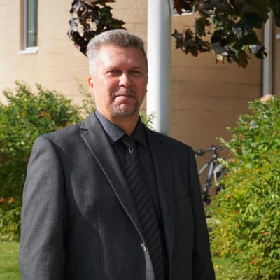 Man i grå kostym står på en innergård.