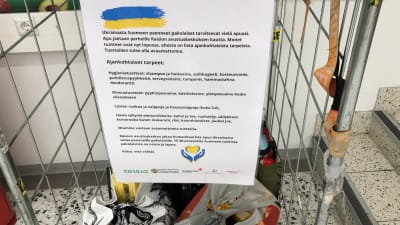 Flera plastpåsar med varor som samlats in till ukrainare, och en A4 med instruktioner för donationer.