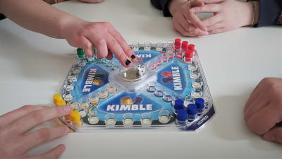 Fyra personer spelar sällskapsspel men bara händerna syns.