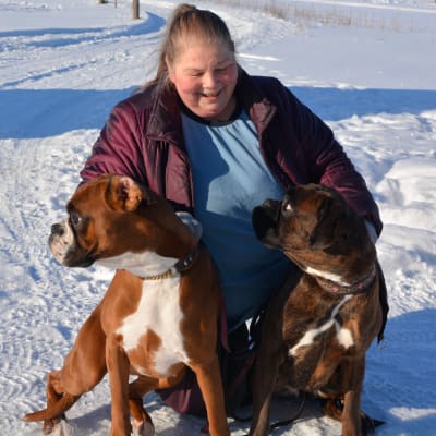 Kvinna i snö med två hundar framför sig