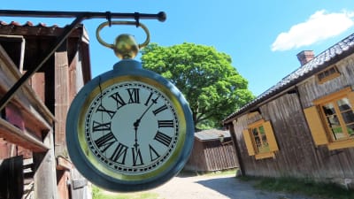 En klocka hänger utanför en vägg på Klosterbacken i Åbo. 