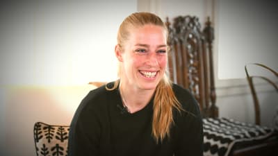 Linda Sällström skrattar hemma i soffan då hon blir intervjuad