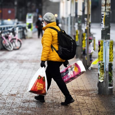 Kasvomaskiin pukeutunut henkilö metroaseman edustalla.