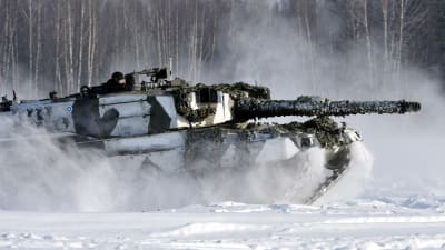 En Leopard-stridsvagn kör framåt i snön.