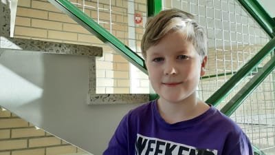 Elton Palmroos, en pojke med ljust hår och lila skjorta, står i en trappa med grönt räcka.