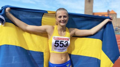Nora Lindahl poserar på Stockholms stadion draperad i den svenska flaggan.
