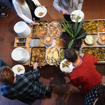 Ett matbuffébord fotat uppifrån med grön sallad, klyftpotatis, såser och andra läckerheter.