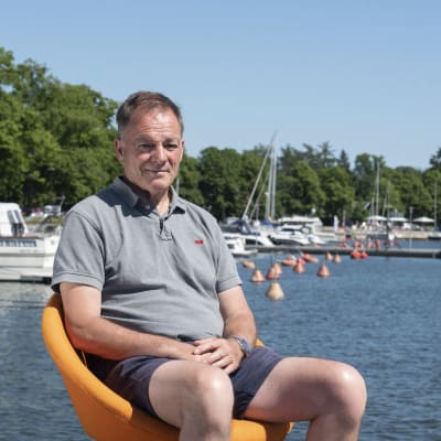 Kilpapurjehtija Tapio Lehtinen istuu oranssilla tuolilla Merisataman laiturilla ja katsoo suoraan kameraan.