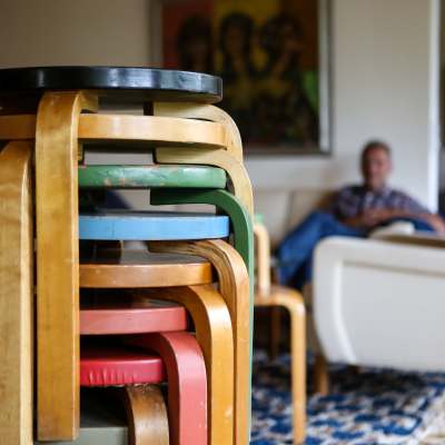 Värikkäitä Alvar Aallon suunnittelemia jakkara 60 -istuimia pinossa olohuoneessa.