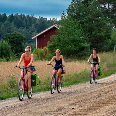Tre kvinnor cyklar i Nagu på Skärgårdens ringväg.