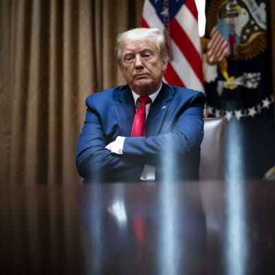 Trump istuu kädet puuskassa Valkoisessa talossa.