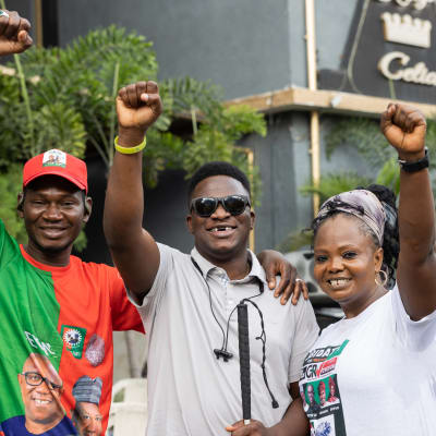 Kolme nigerialaista nuorta nyrkit koholla vaalitilaisuudessa. 