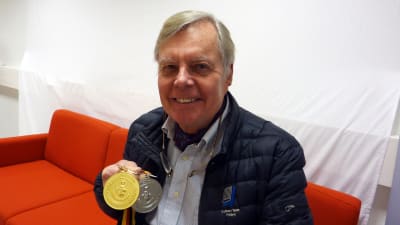 Nils-Gustav Höglund sitter i en soffa med två OS-medaljer i handen.