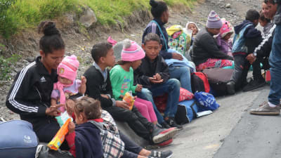 Venezuelanska familjer väntar vid vägen på gränsen mellan Venezuela och Ecuador.