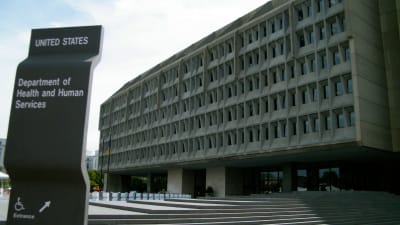 En grå betongfasad i fem våningar med små fönster. I förgrunden en skylt som upplyser att här finns USA:s hälso- och socialministerium.