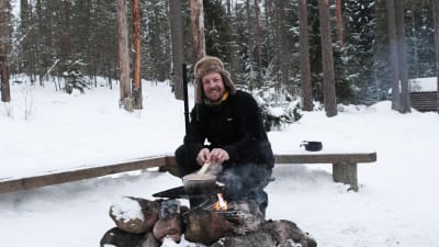 MIkko Peltola valmistaa ruokaa nuotiolla Nuuksiossa.