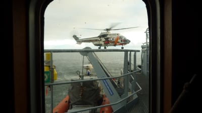 Helikopter kommer för att lämna över den nödställde till Sjöbevakningens fartyg.